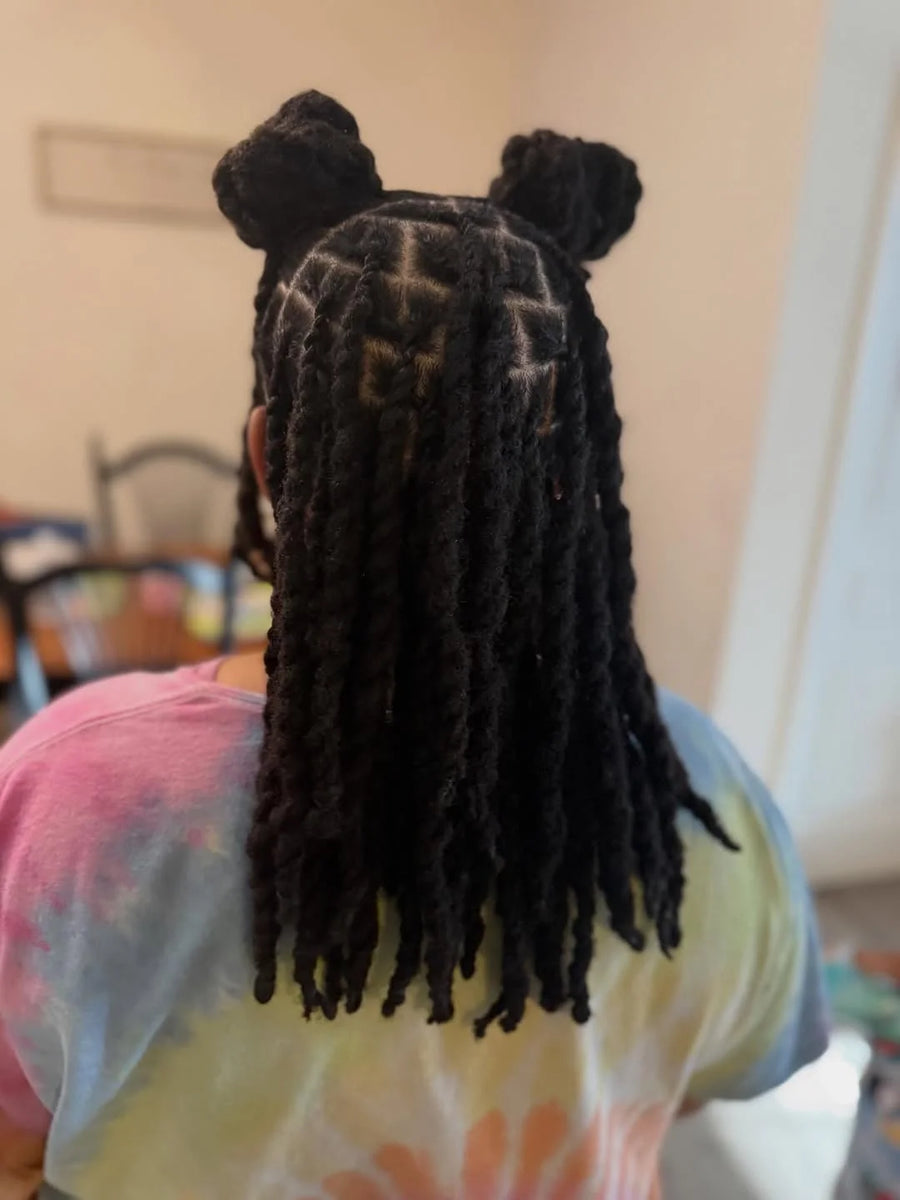 Person with styled hair in a room with a chair and table in the background