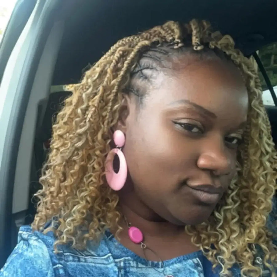 Woman with blonde braided hair wearing pink earrings inside a vehicle
