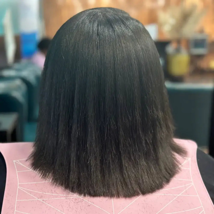 Back view of a person with straight black hair in a salon setting