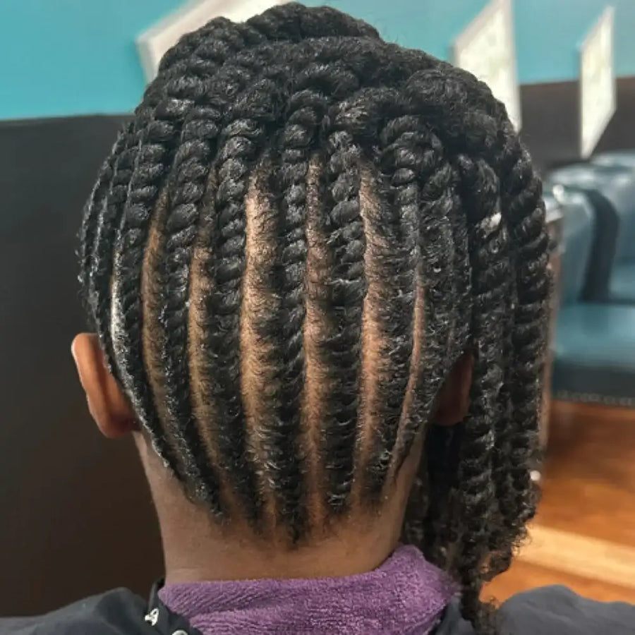 Person with braided hair sitting in a salon chair.
