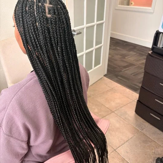 Person with long braided hair in a salon setting
