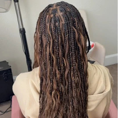 Person with long braided hair sitting in a chair, back view