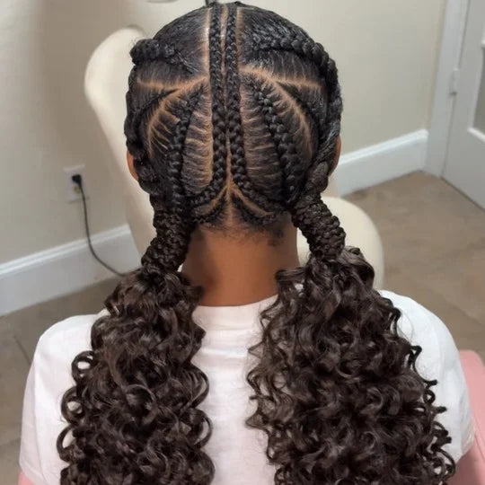 Person with braided hair styled in cornrows with loose curls at the ends, sitting on a chair.