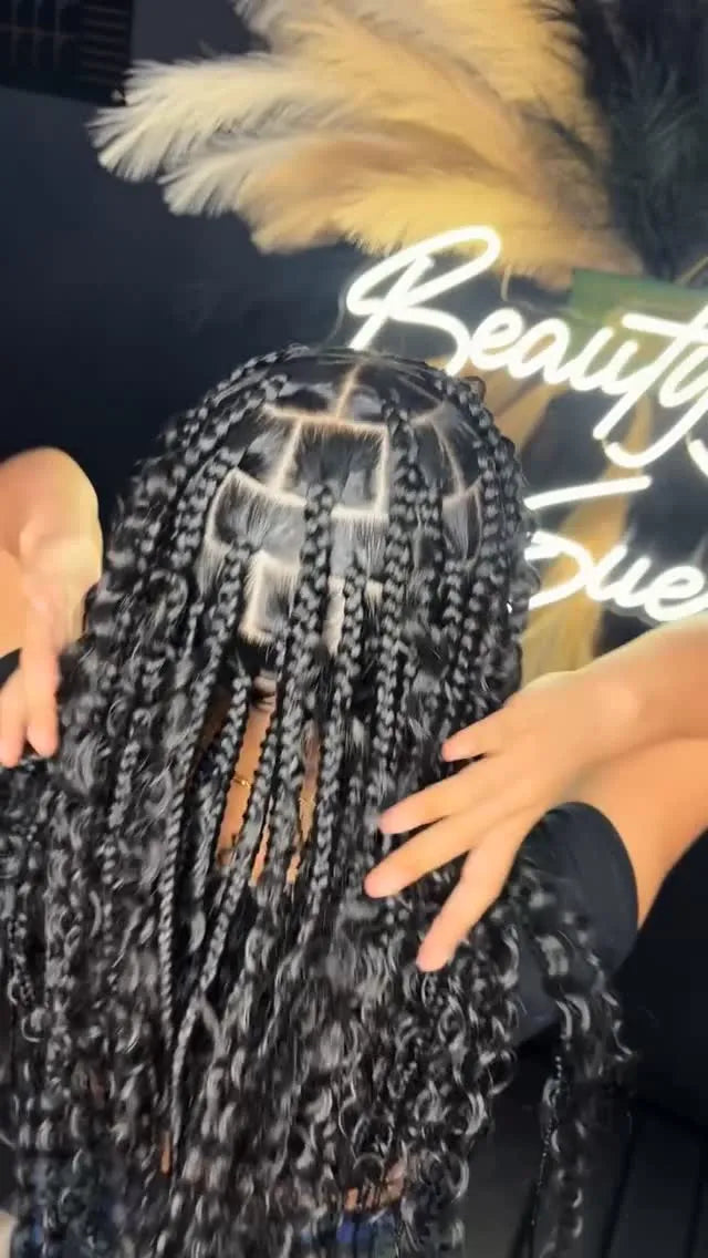Person with braided hair in a salon setting with neon sign in the background