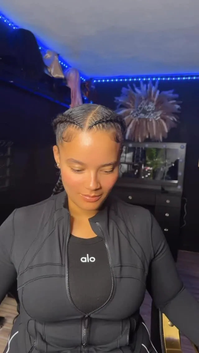 Person wearing a black jacket with 'alo' logo in a room with decorative lights and plants.