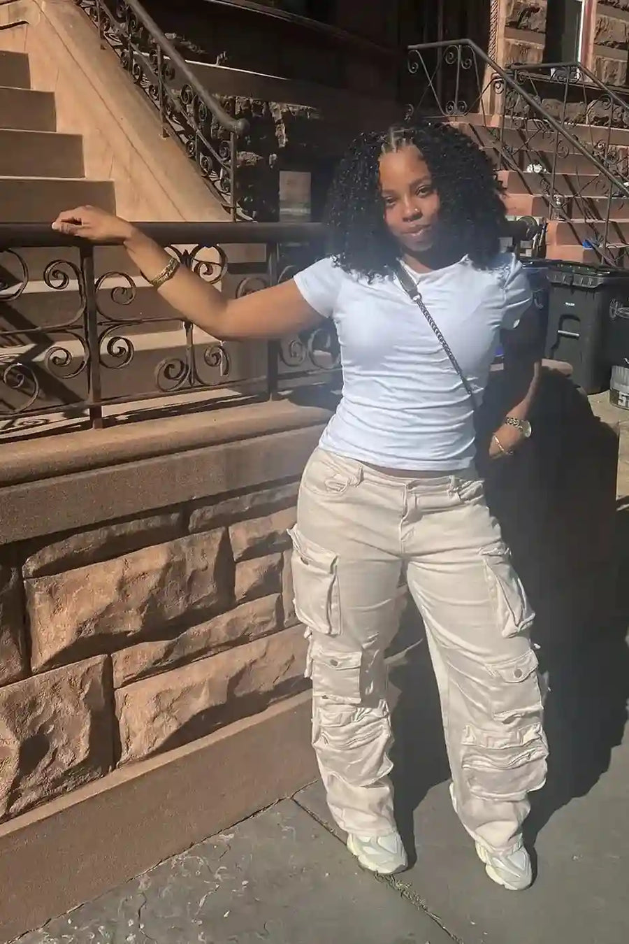 Woman in a white shirt and beige cargo pants standing on stone steps.