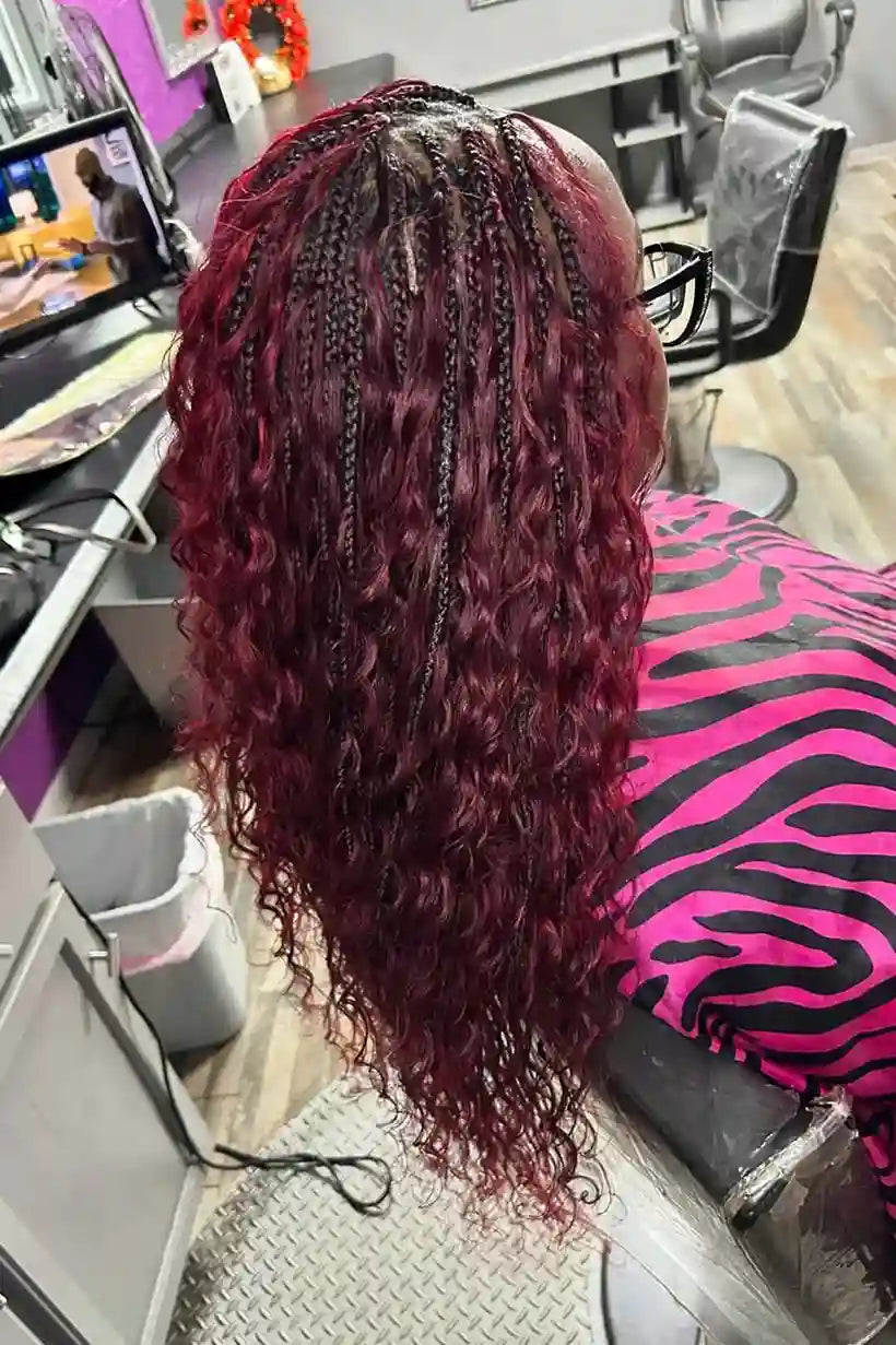 Person with burgundy braided hair in a salon setting