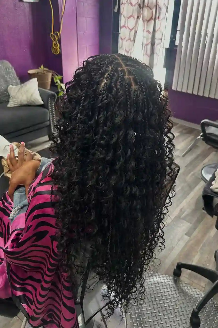 Person with long, curly hair sitting in a salon chair.
