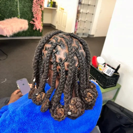 Person with braided hair sitting on a blue chair in an indoor setting.