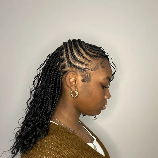 Person with styled braided hair wearing a brown sweater against a plain background