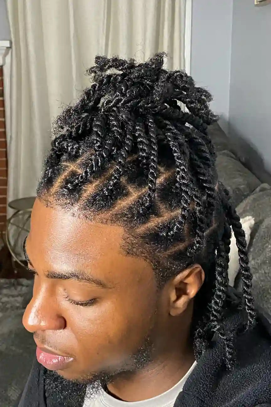 Person with styled braided hair in a room with a couch and window.