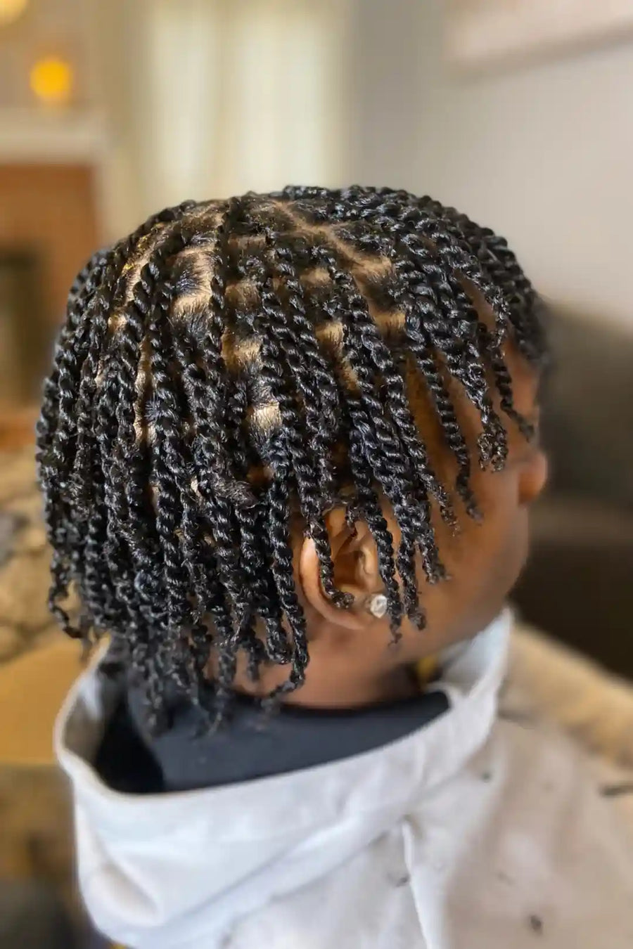 Person with braided hair wearing a white jacket indoors