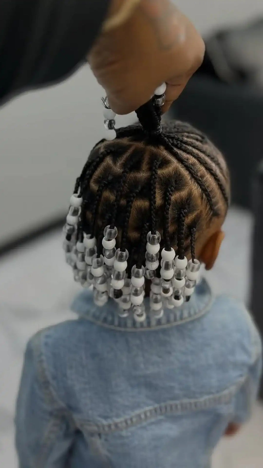 Person styling braids with beads on a blurred background