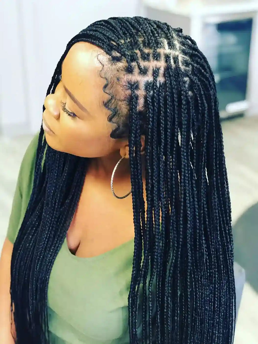 Person with braided hair wearing a green top indoors.