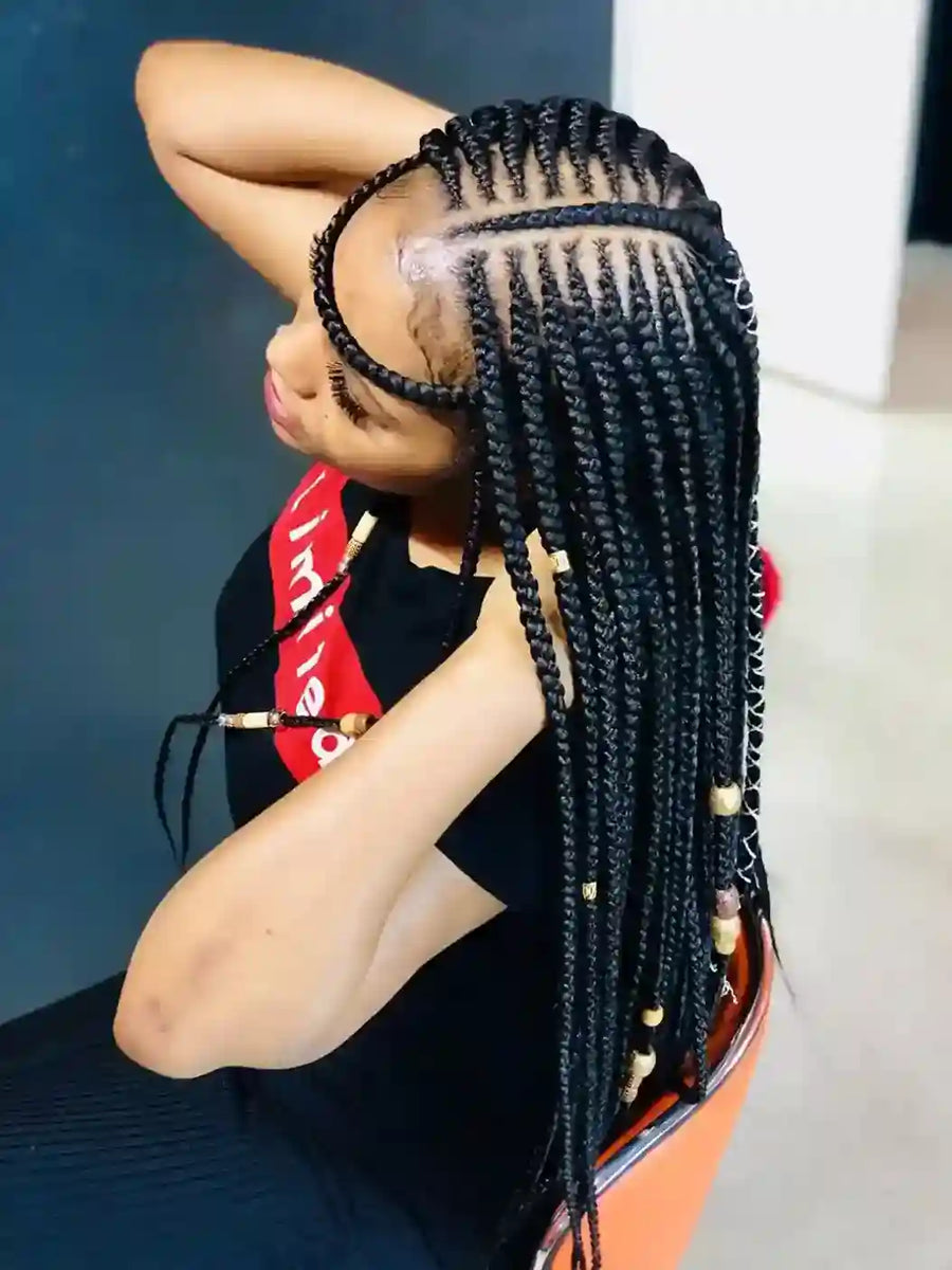 Person with braided hair wearing a black outfit with red accents.