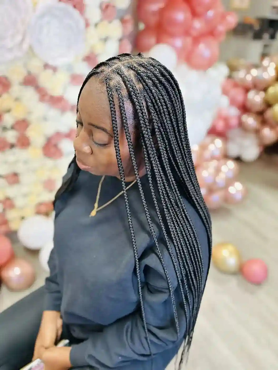 Person with braided hair in front of a colorful balloon display