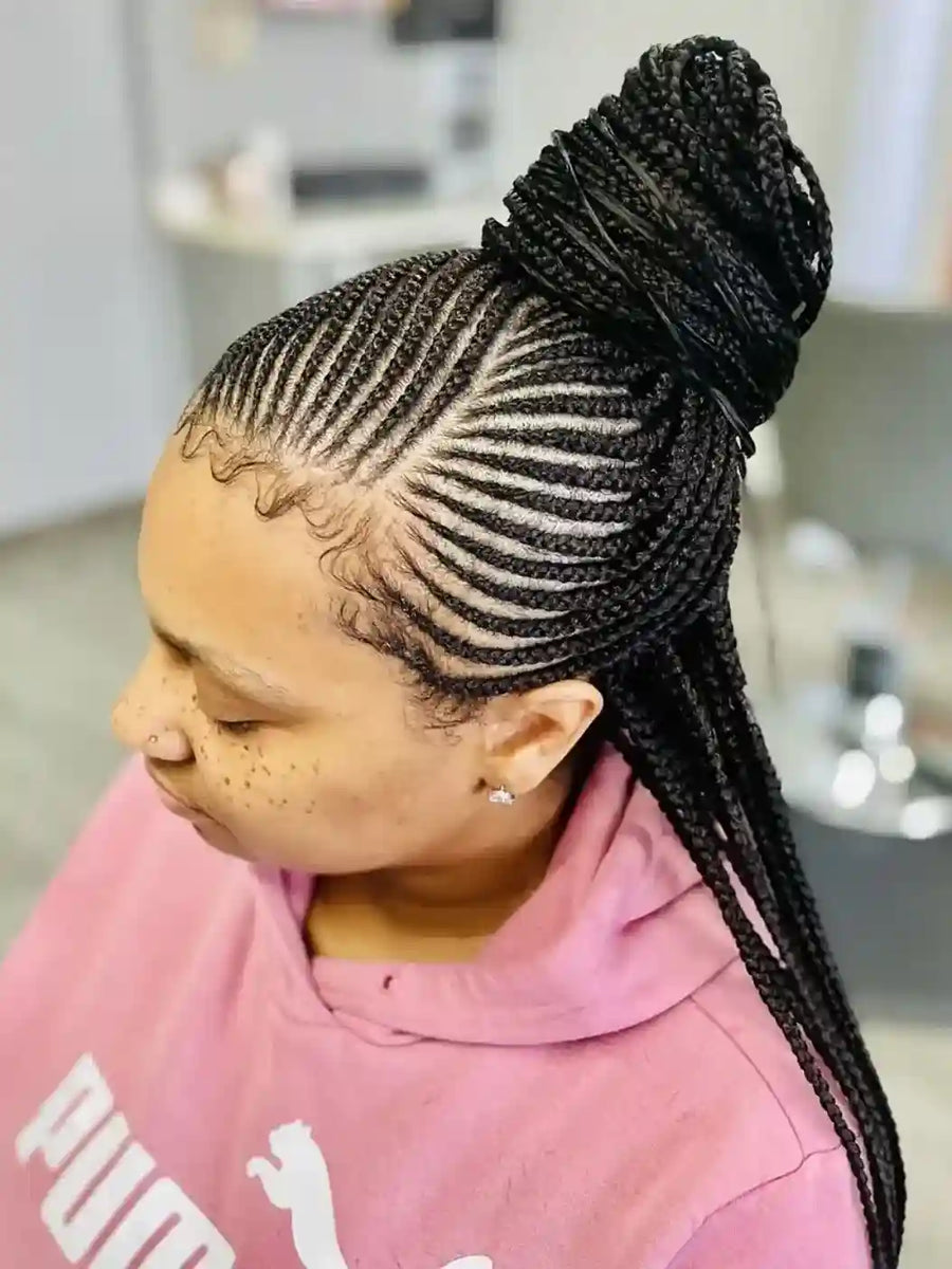 Person with braided hair styled in cornrows, wearing a pink hoodie.