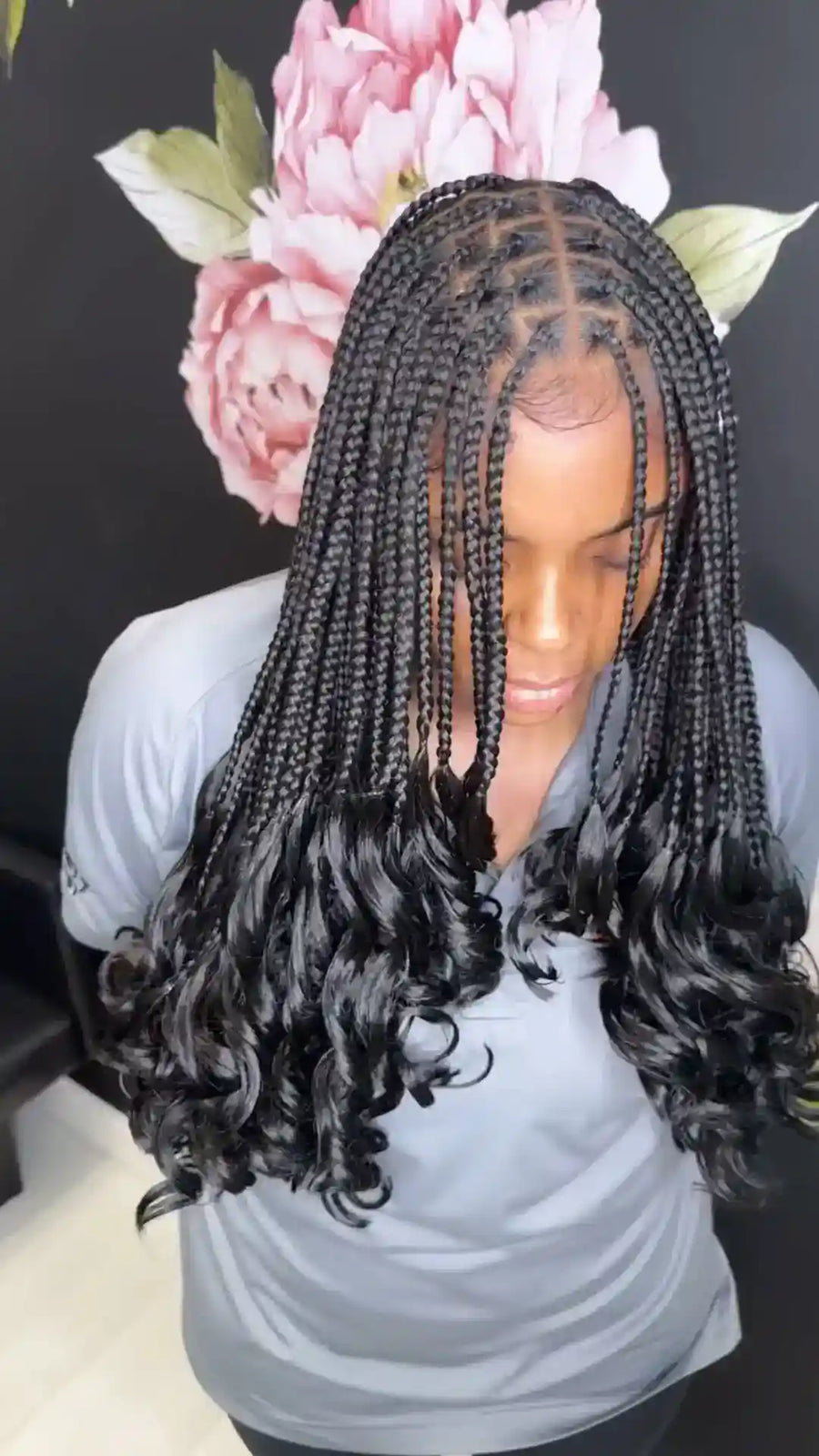 Person with styled hair in braids against a floral background