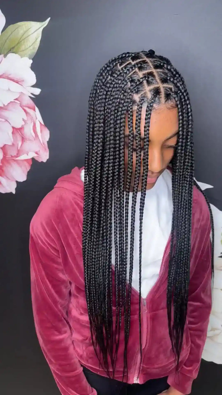 Person with braided hair wearing a pink jacket against a floral background