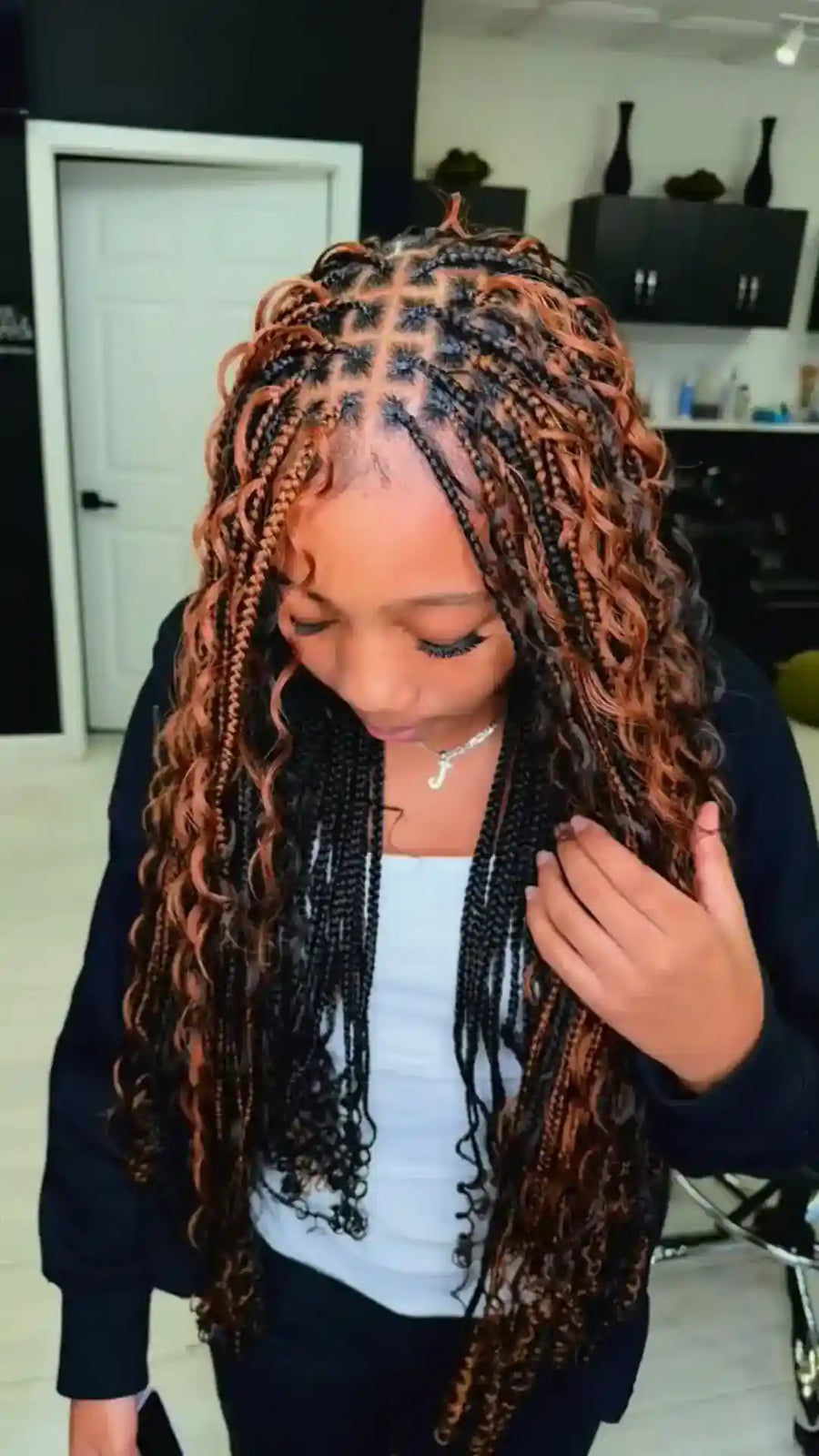 Person with long, styled hair in a room with a white door and shelves.