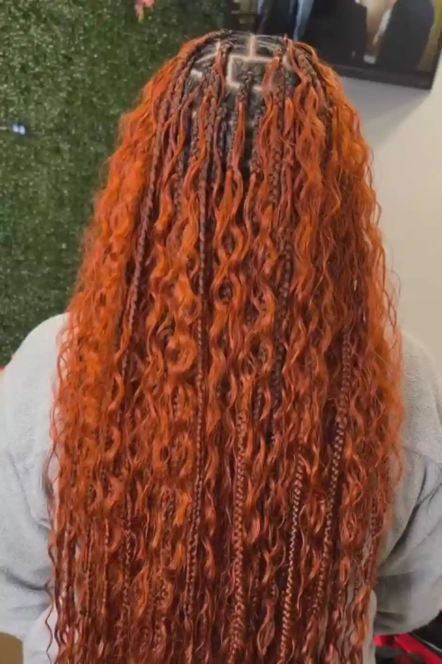 Person with long, wavy, orange hair styled in cornrows.