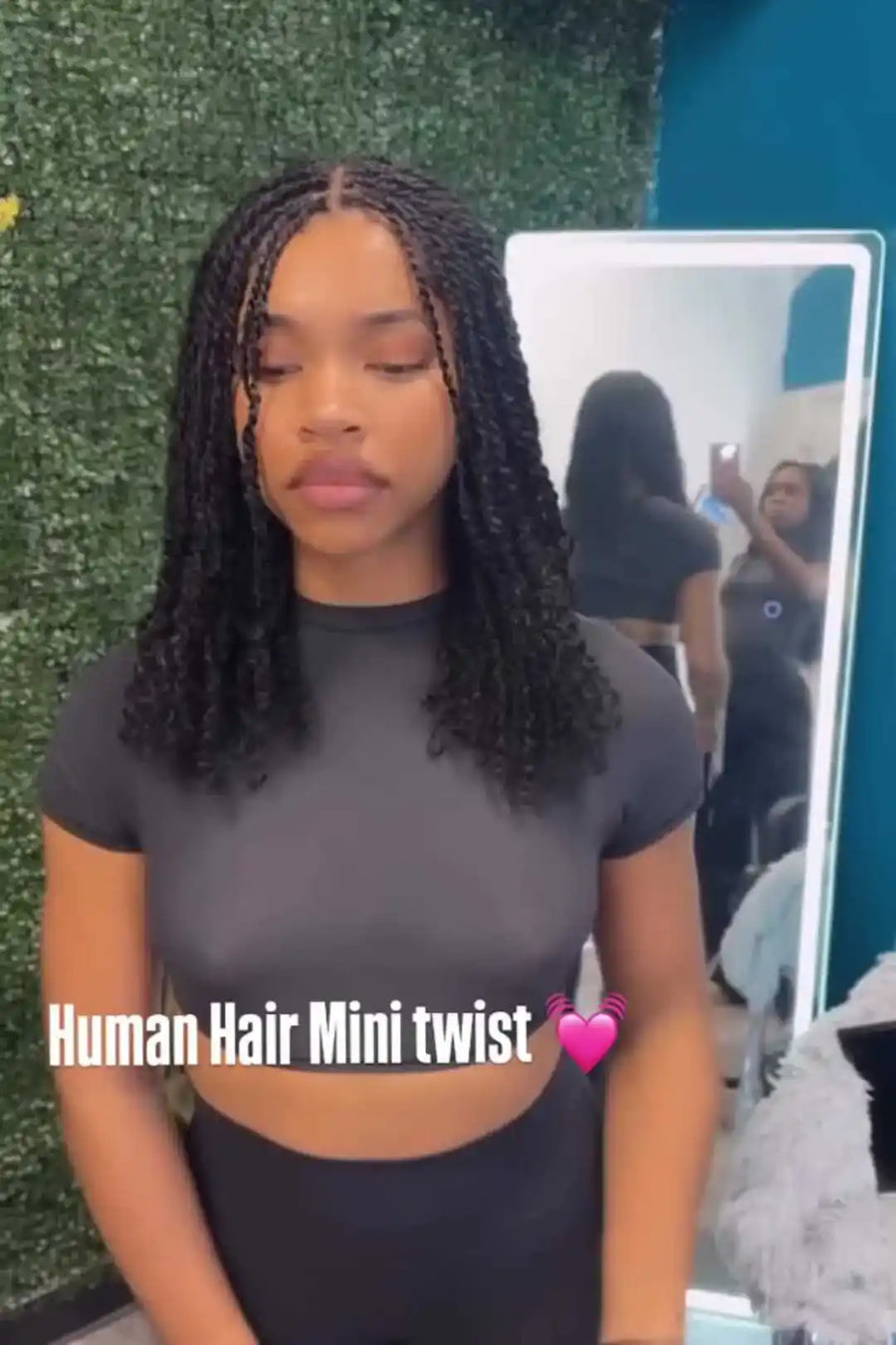 Woman with human hair mini twists standing in front of a mirror with text overlay.