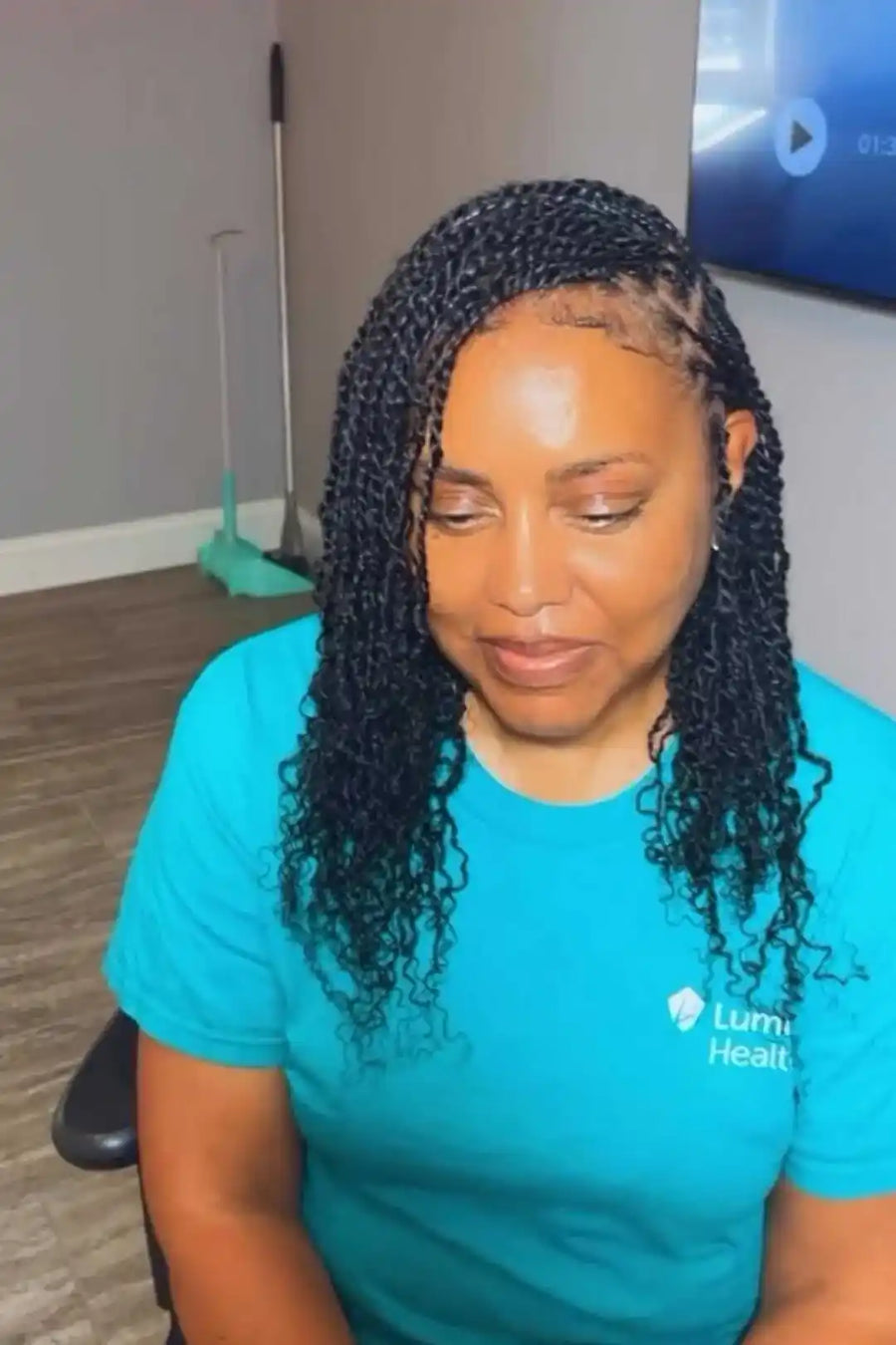 Person wearing a blue shirt with a logo, sitting indoors.