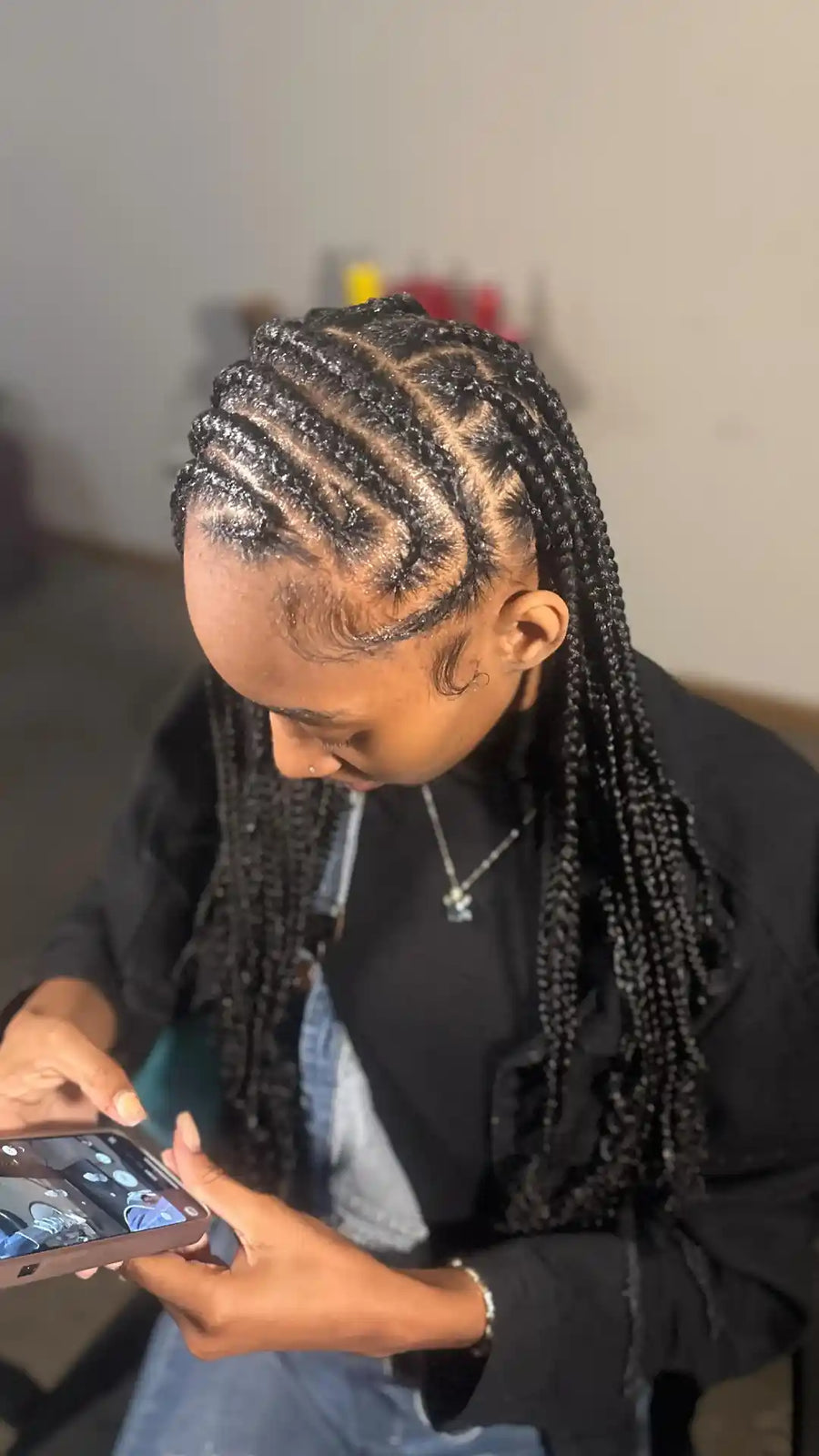 Person with braided hair using a phone indoors