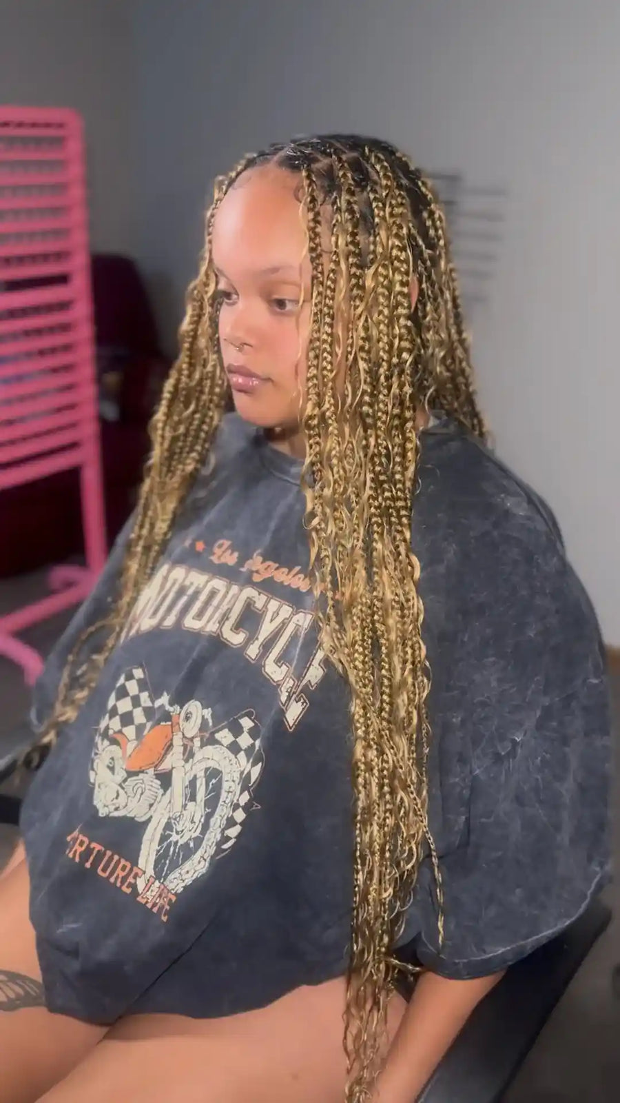 Person with braided hair wearing a dark blue t-shirt with graphics and text.