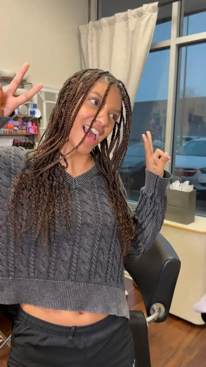 Long small knotless braids with brown tones and soft wavy ends, hairstylist located in Rockwall, TX