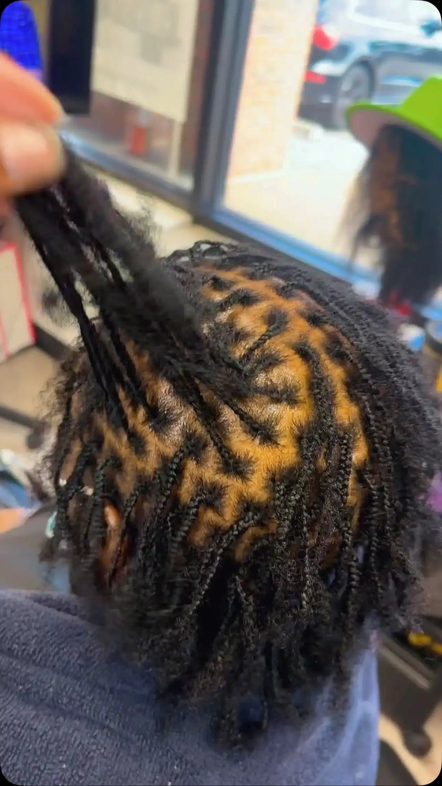 Small black braids with neat square parting and loose natural curly hair extensions during installation, Stylist located in Bartlett, TN