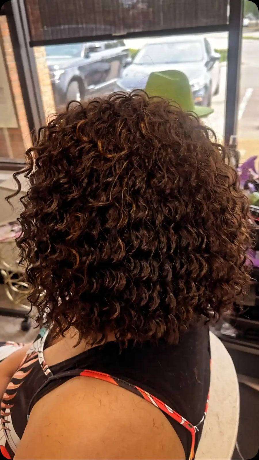 Short voluminous curly bob hairstyle with dark brown hair, warm brown highlights, and defined spiral curls, Stylist located in Bartlett, TN
