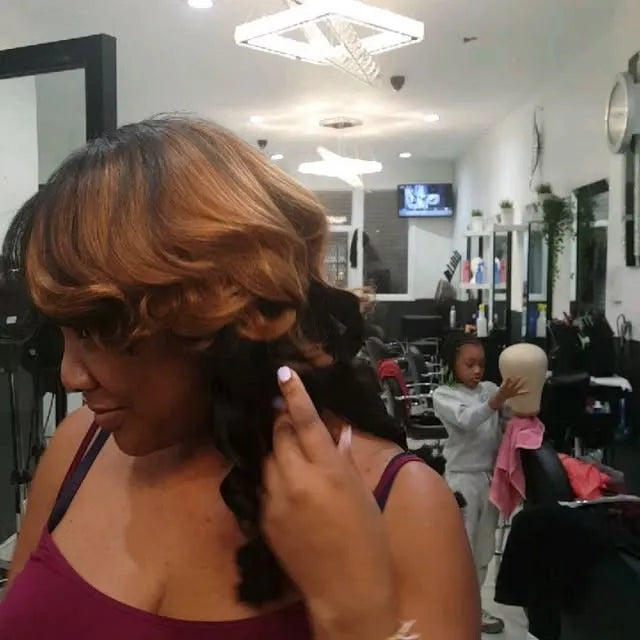 Woman getting hair styled in a salon with another person in the background.