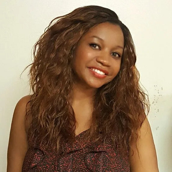 Woman with long, wavy hair smiling against a plain background