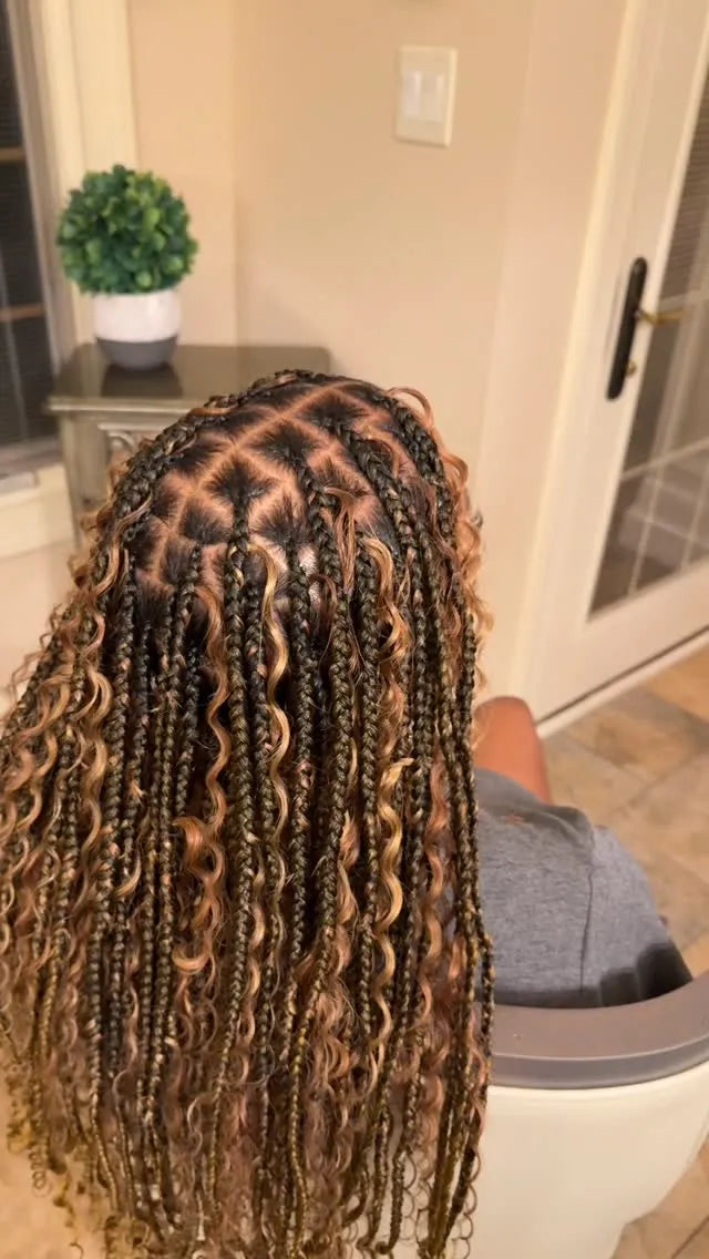 Person with braided hair sitting on a couch in a home setting