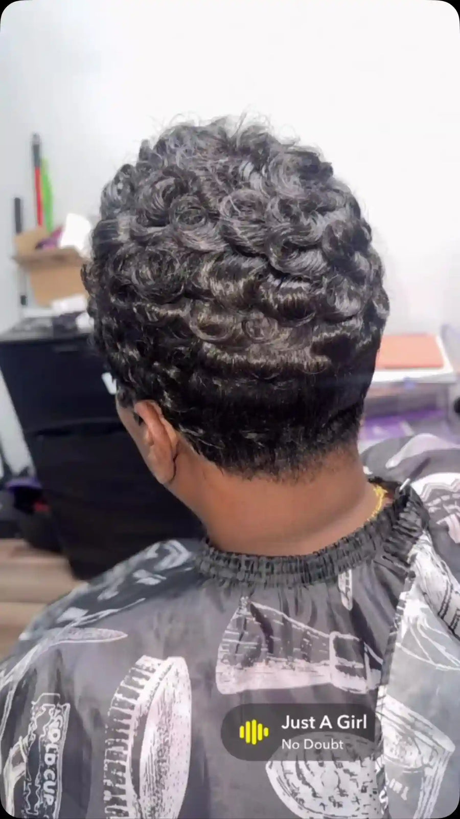 Short black curly pixie cut with layered pin curls and a smooth tapered neckline, hairstylist located in Chesterfield, VA
