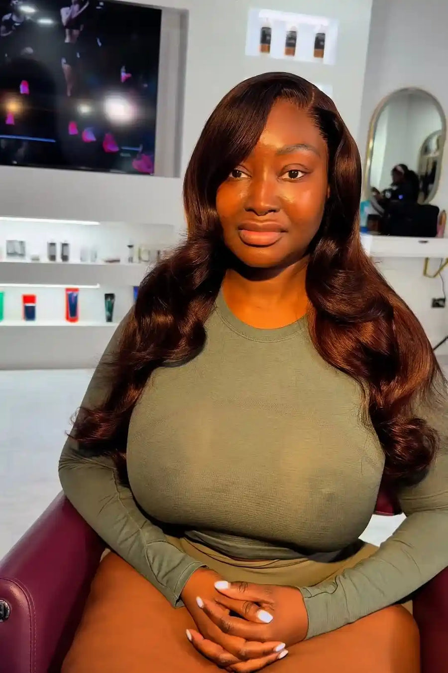 Woman sitting on a couch in a room with shelves and a mirror.