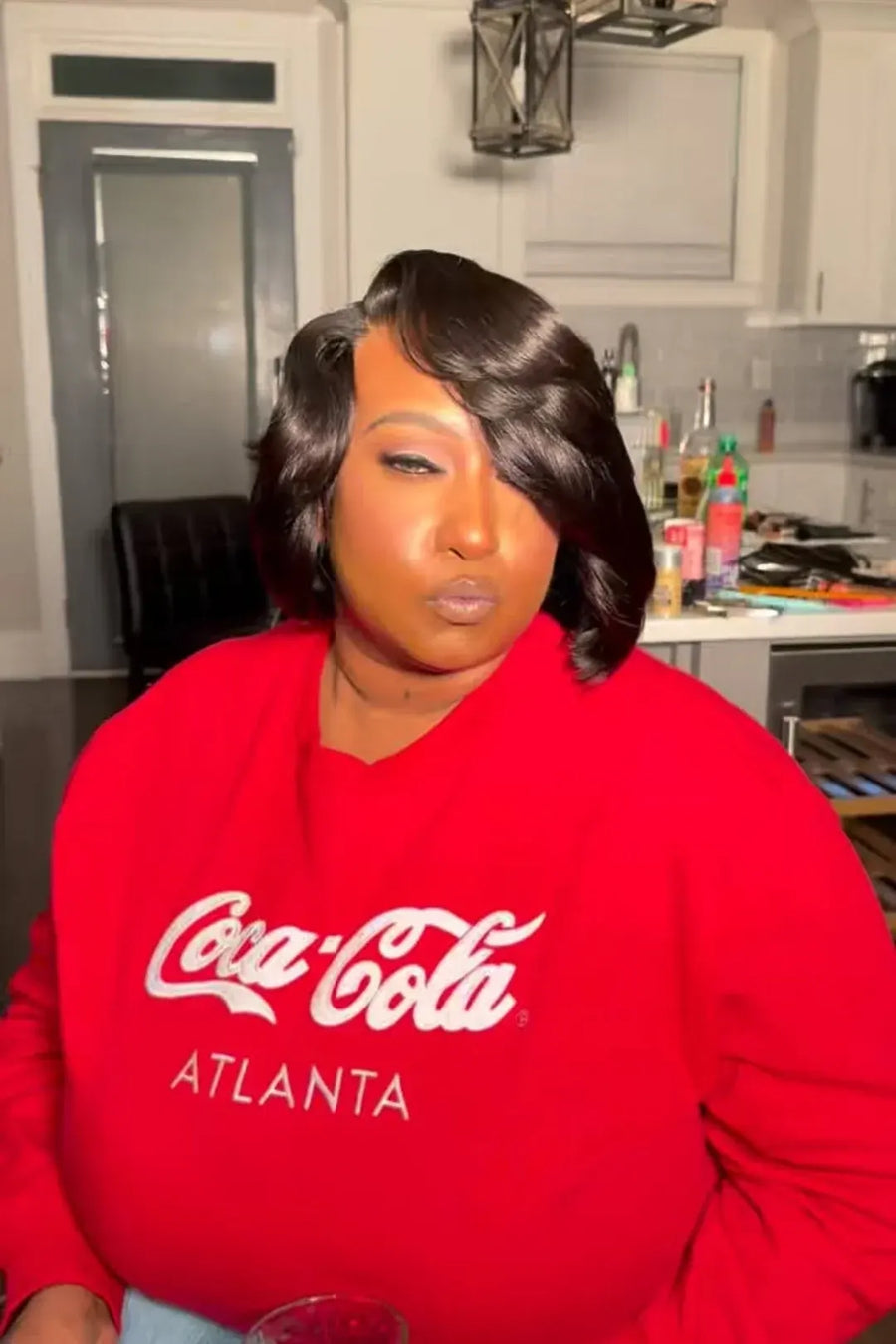Person wearing a red Coca-Cola sweatshirt in a kitchen setting