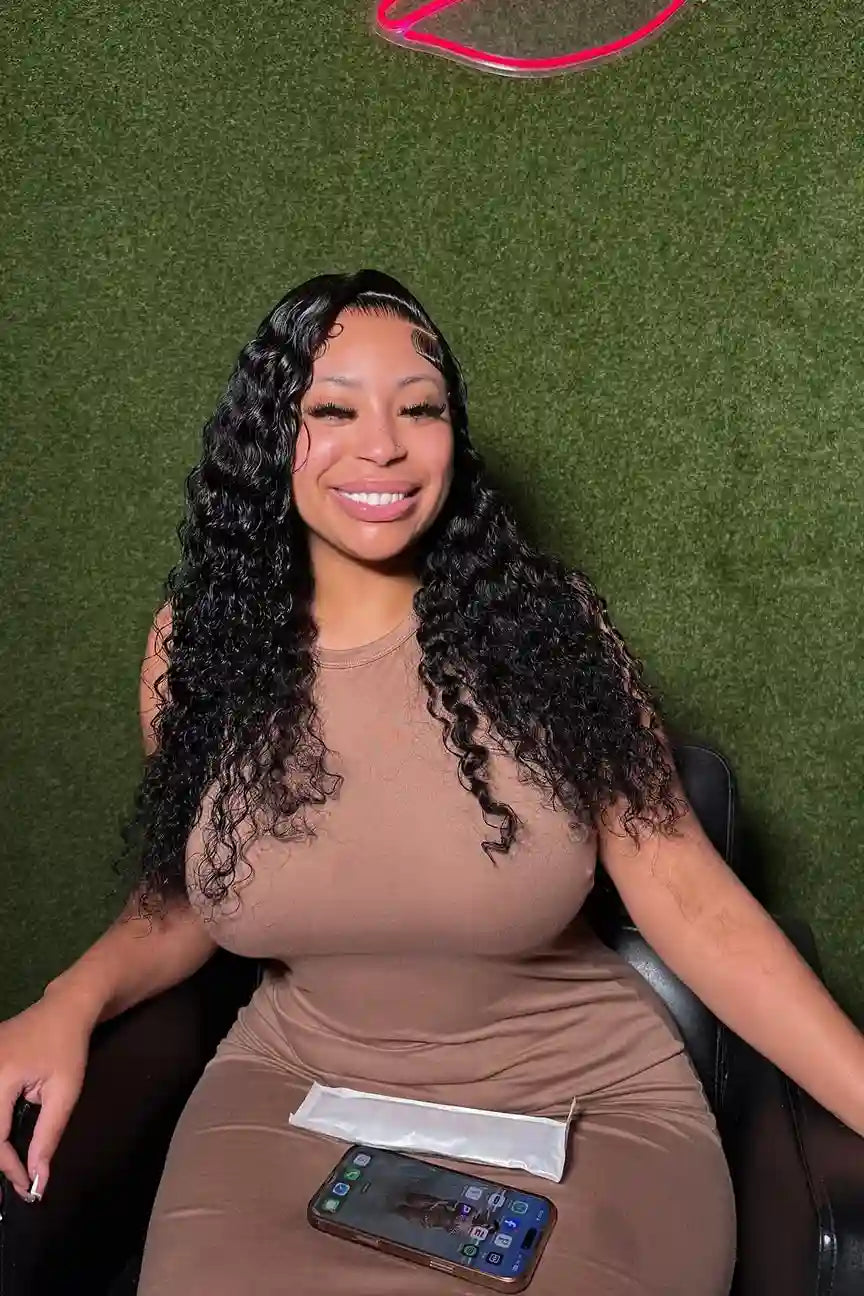 Woman with long, curly hair sitting on a green couch with a phone and paper in front of her.