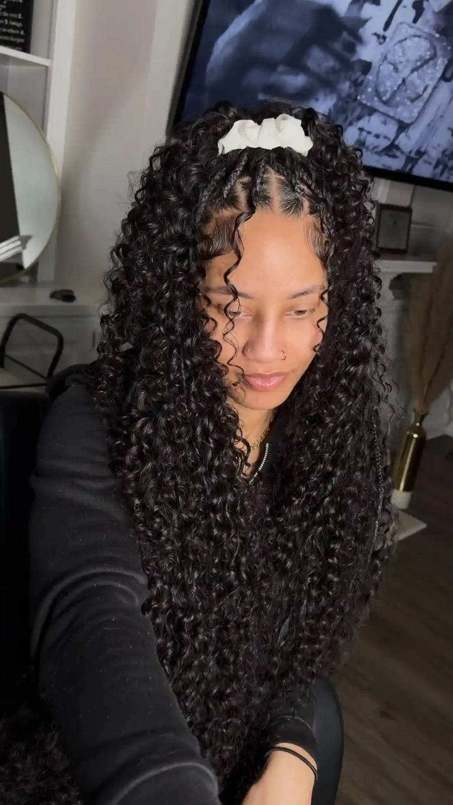 Person with long, curly hair sitting indoors in a casual setting.