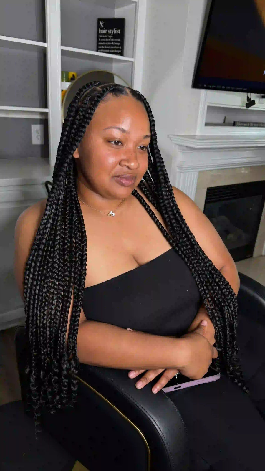Woman with braided hair sitting in a salon chair.