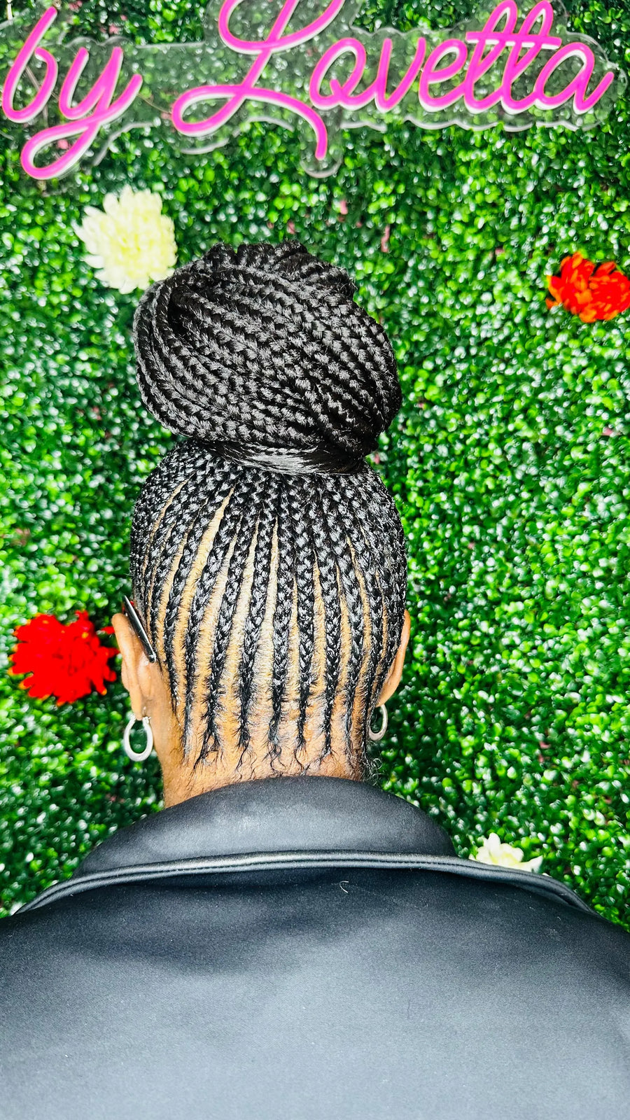 Person with braided hair against a green textured background with flowers, featuring 'by Lavelta' text.