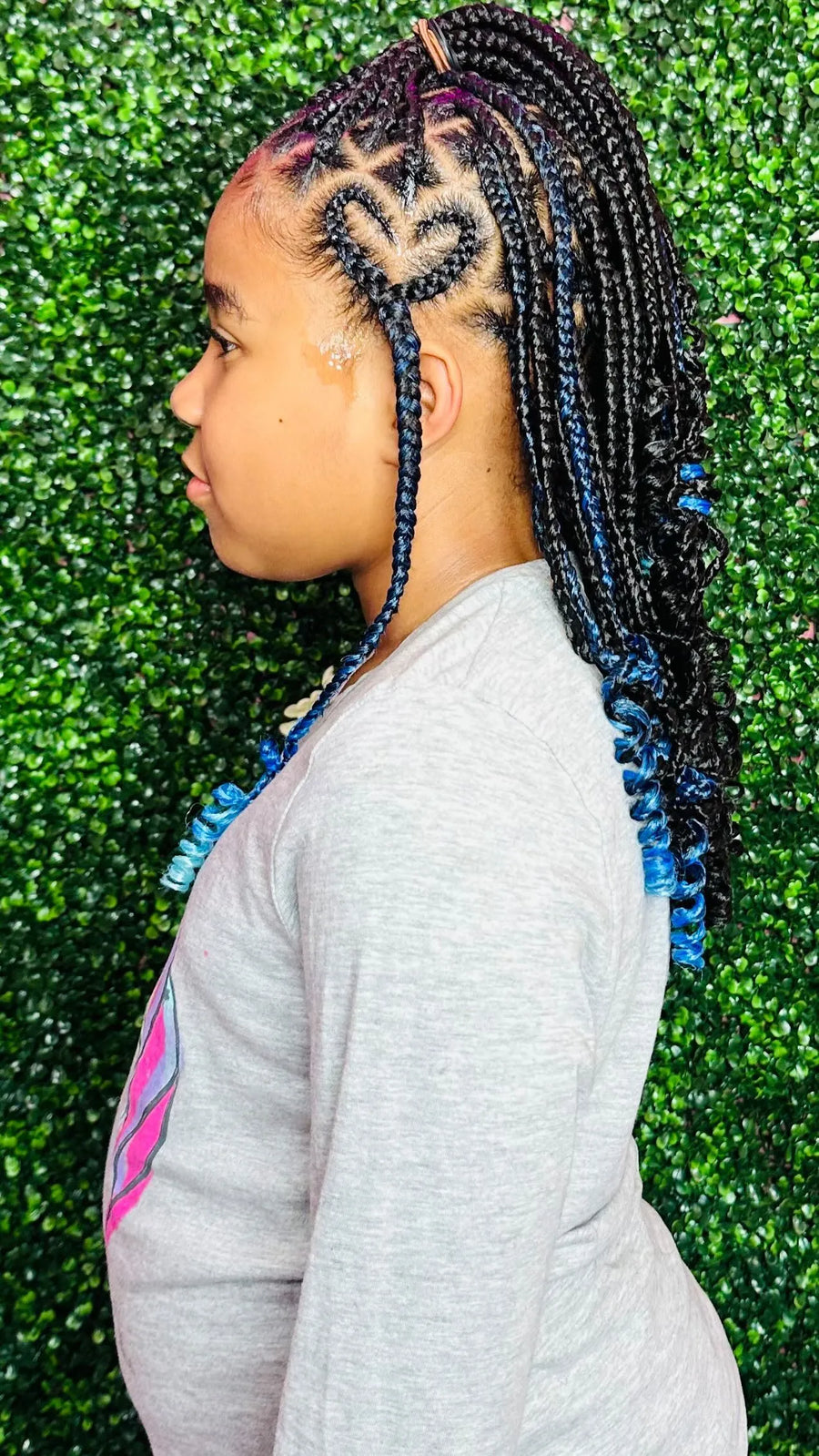 Person with braided hair in front of a green textured background