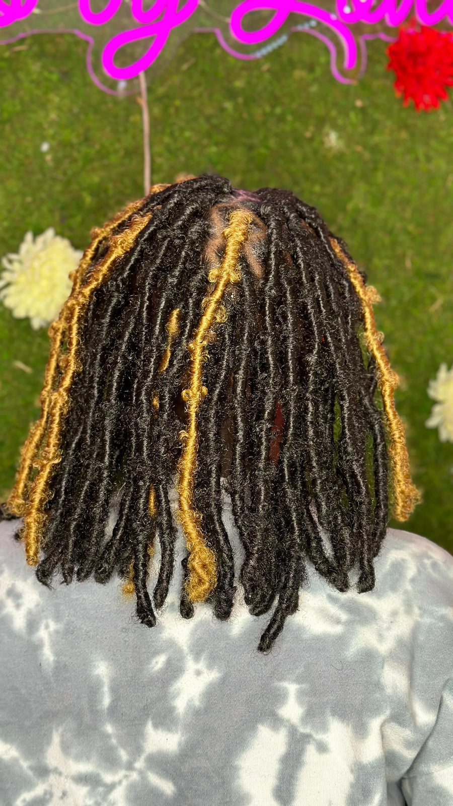 Person with black and gold braided hair against a blurred natural background