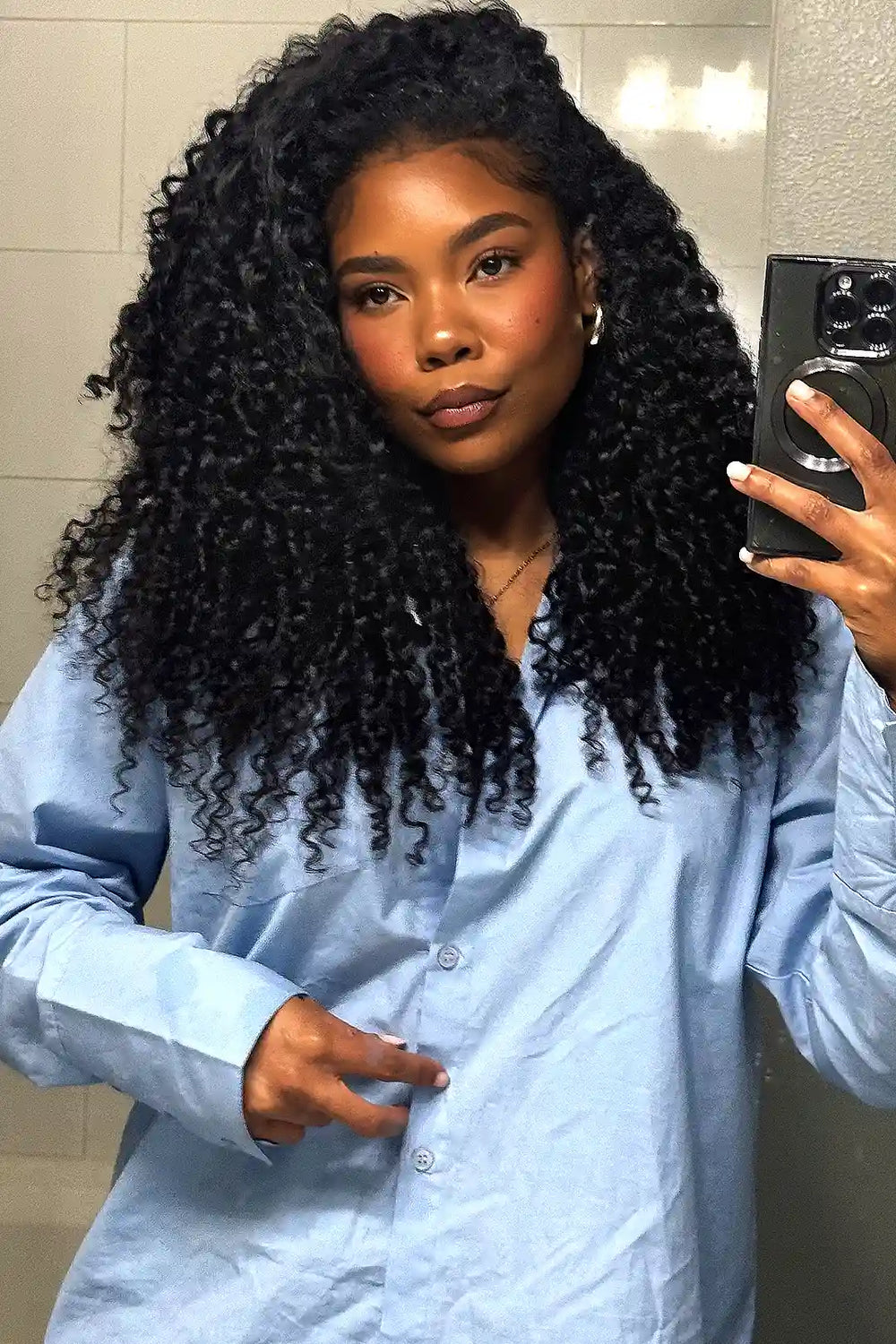Voluminous black spiral curly crochet hair with feathering, double-drawn for fullness, modeled by a Black woman wearing a light blue shirt.