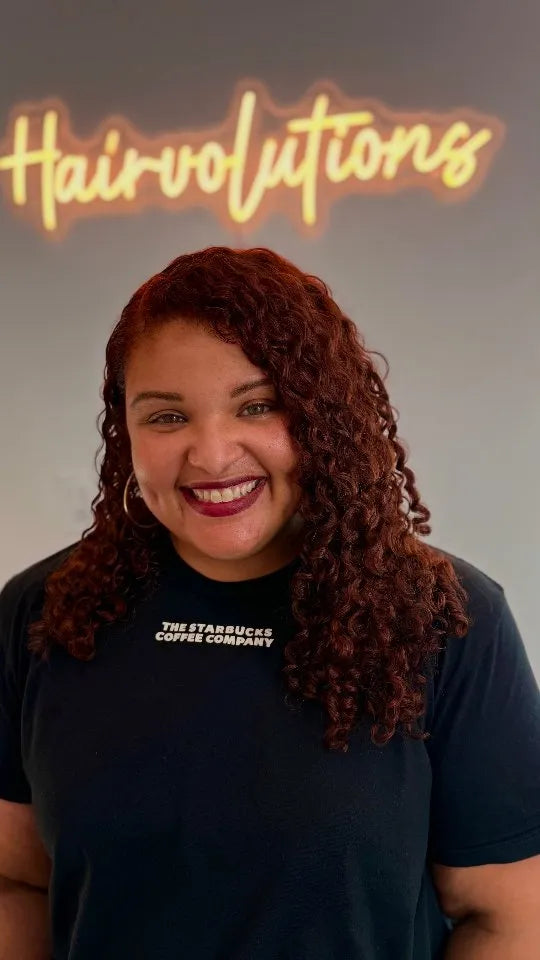 Shoulder-length burgundy curly hairstyle with a deep side part and defined spiral curls, Stylist located in Gilbert, AZ