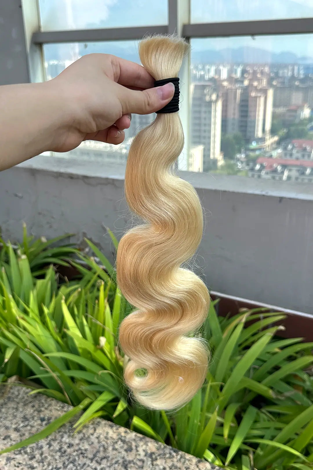 Outdoor picture of single drawn 613 blonde body wave bulk human hair for braiding
