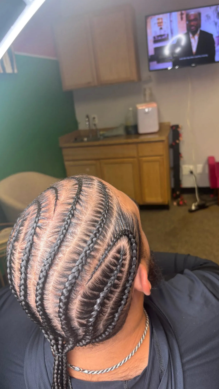 Men’s curved stitch cornrows with a detailed side swirl pattern and braided tail, hairstylist located in Arlington, TX
