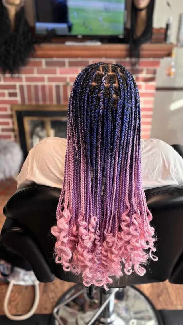 Person with a wig featuring blue to pink gradient hair color on a salon chair.