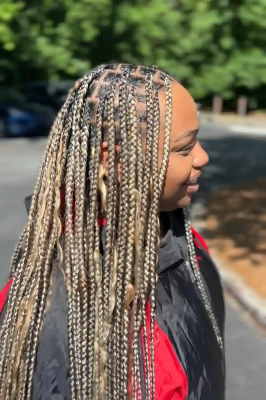 Person with braided hair standing outdoors on a sunny day